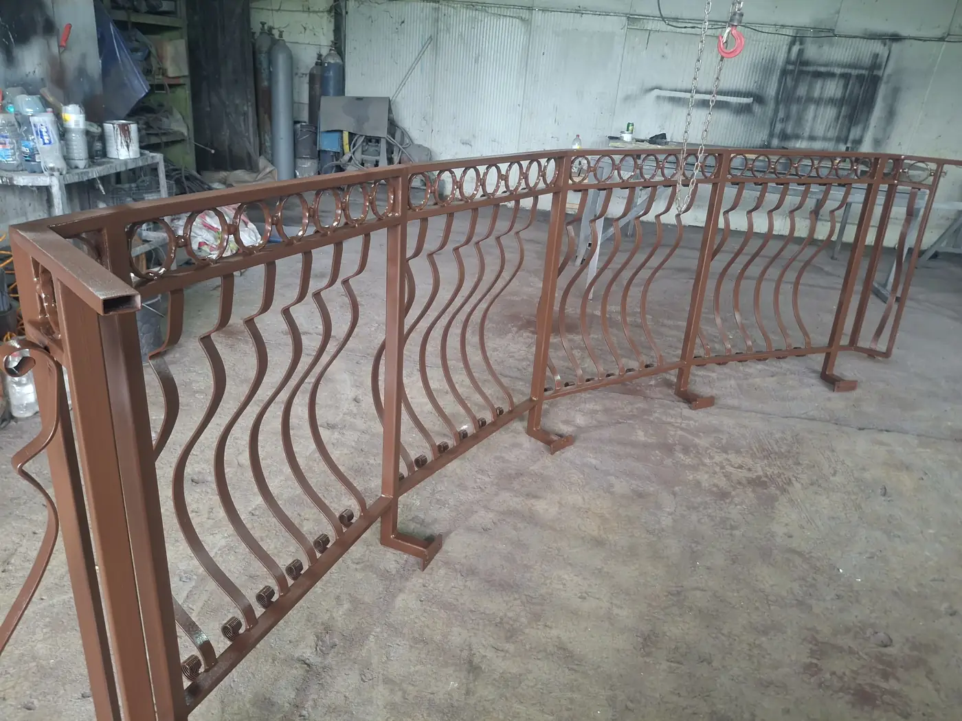 Curved metal railing painted brown, in the workshop